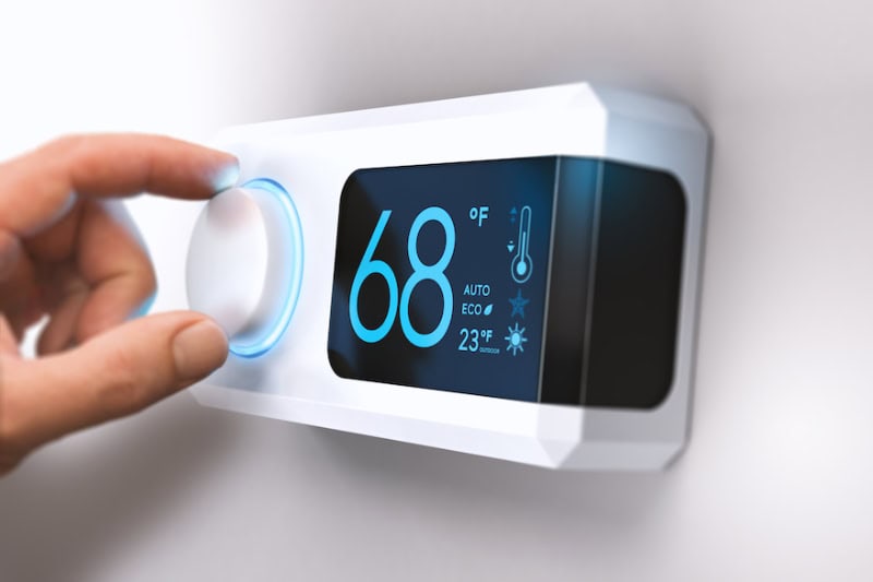 Hand turning a home thermostat knob.