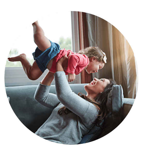 Mother playing with daughter on couch in Turlock after HVAC services from Pacific Breeze Air Systems.
